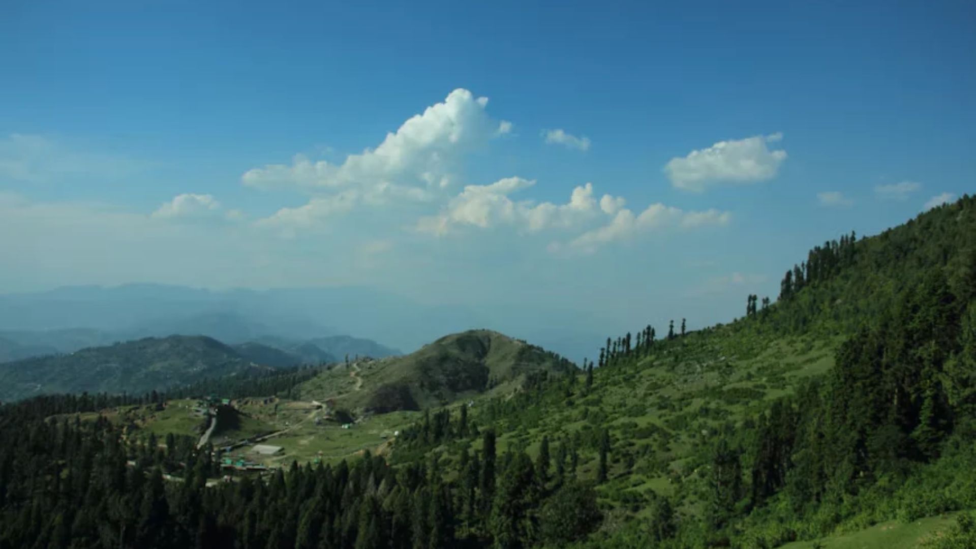 lush green hills with scattered trees and beautiful blue sky -best backpacking destinations in India